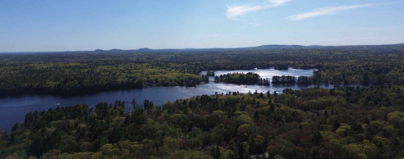 Aerial view of a lake with wooded islands and hills in the distance